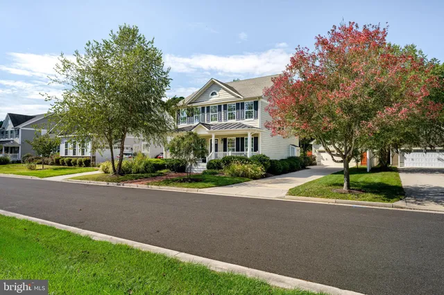 a white house with a a yard and a large tree