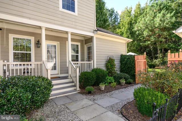 a view of a house with potted plants and a bench