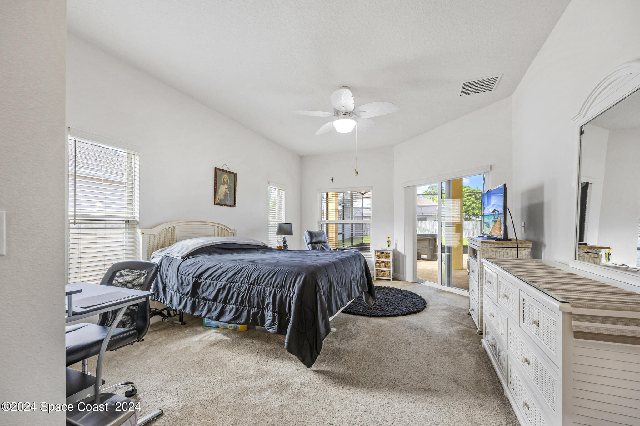 572 Glenbrook Circle Rockledge, FL 32955 - Photo 25 of 35 a spacious bedroom with a bed a table and a chandelier