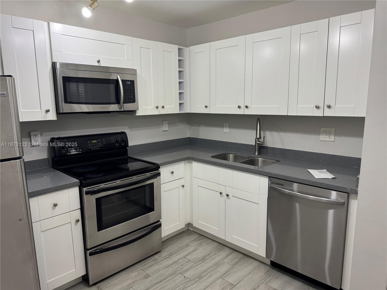 721 North Pine Island Road, Unit 201 Plantation, FL 33324 - Photo 4 of 18 a kitchen with white cabinets and stainless steel appliances