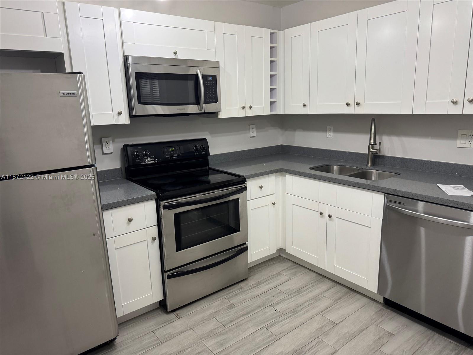 721 North Pine Island Road, Unit 201 Plantation, FL 33324 - Photo 6 of 18 a kitchen with granite countertop white cabinets and white appliances
