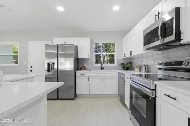 a kitchen with stainless steel appliances granite countertop a refrigerator stove a sink dishwasher and microwave with wooden cabinets