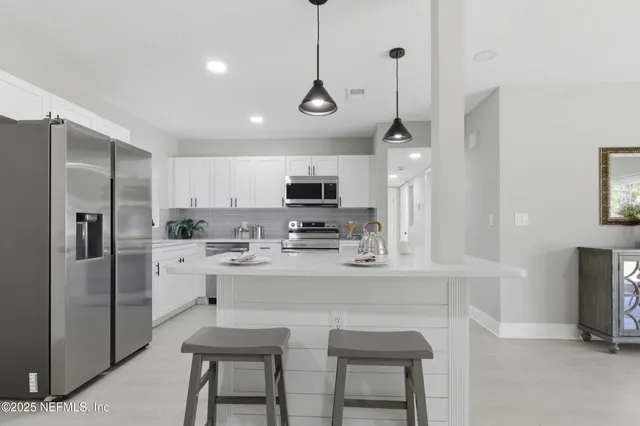 a kitchen with stainless steel appliances granite countertop a sink a stove a refrigerator and island with wooden floor