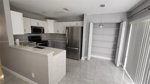 a kitchen with a refrigerator a stove top oven and cabinets