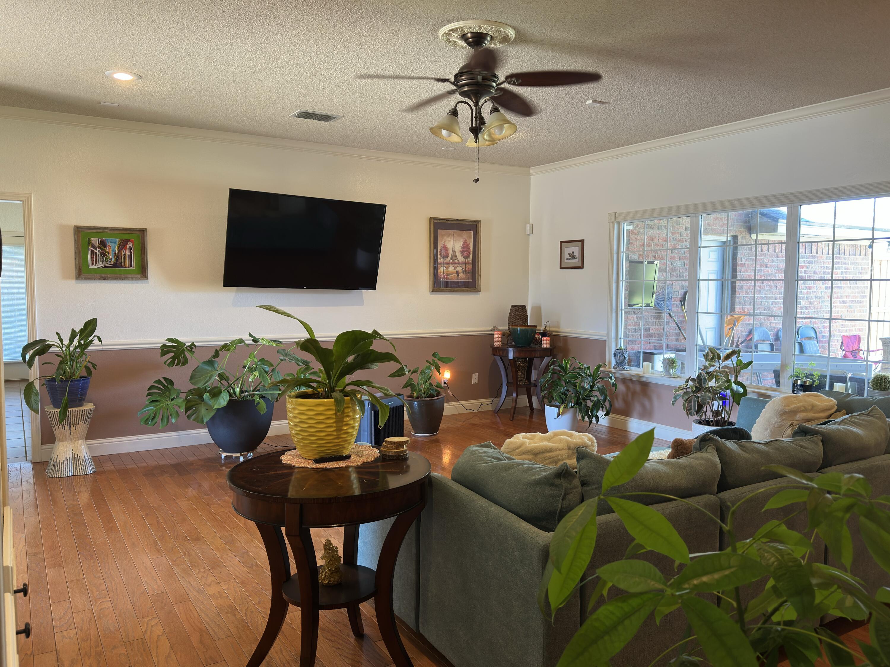 4902 103rd Street Lubbock, TX 79424 - Photo 10 of 23 a living room with furniture a flat screen tv and a potted plant