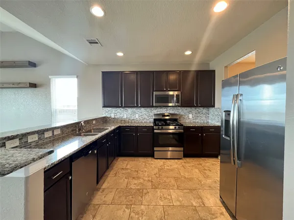 a kitchen with granite countertop stainless steel appliances and wooden cabinets