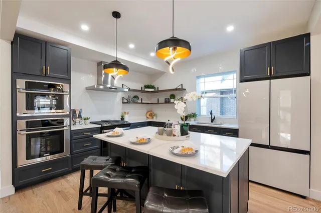 a kitchen with stainless steel appliances granite countertop a sink a stove a refrigerator a center island a dining table and chairs