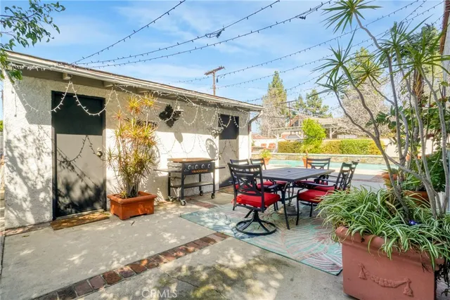 a view of a patio with table and chairs potted plants and large tree