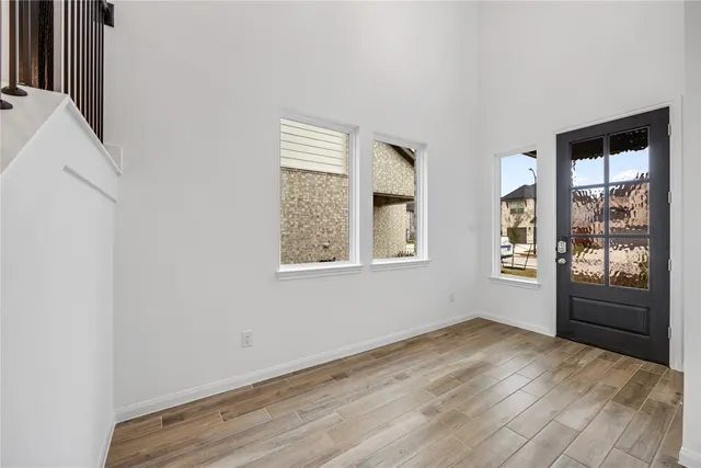 a view of an empty room with window and wooden floor