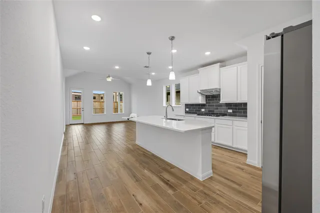 a view of kitchen with cabinets wooden floor and front door