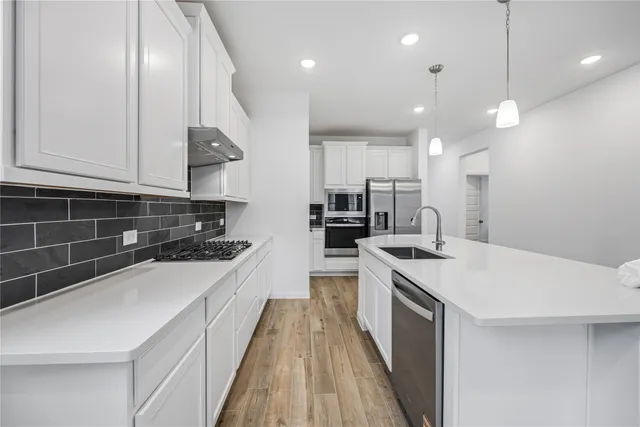 a kitchen with a sink a counter top space stainless steel appliances and cabinets