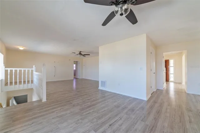 a view of a room with wooden floor and a chandelier fan