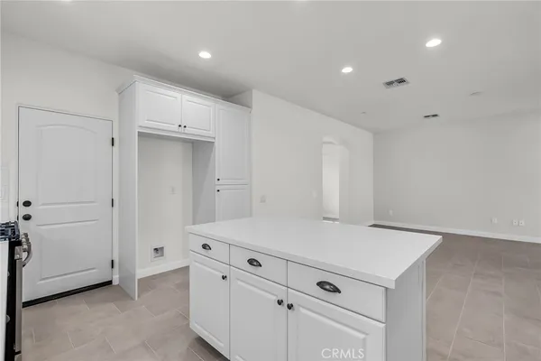 a view of kitchen with refrigerator and white cabinets
