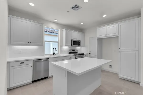 a kitchen with kitchen island a sink stainless steel appliances and cabinets