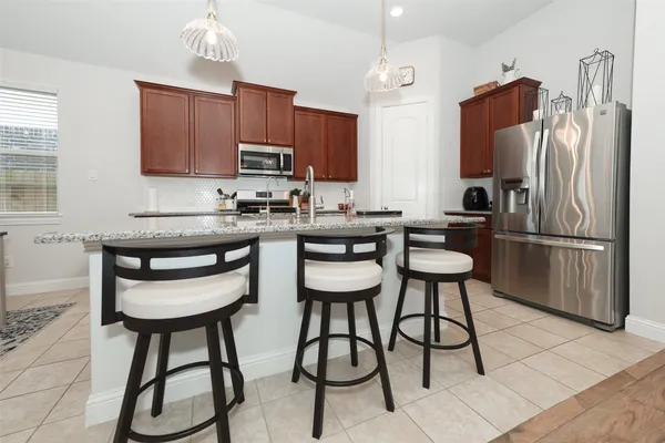 a kitchen with stainless steel appliances kitchen island a table chairs refrigerator and microwave