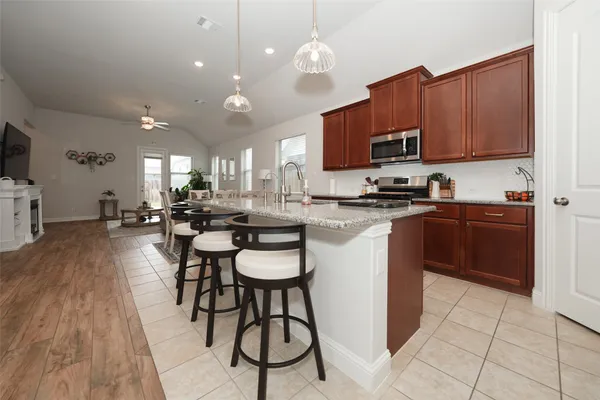 a kitchen with stainless steel appliances a sink a stove a refrigerator cabinets and dining table