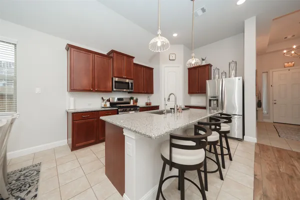 a kitchen with stainless steel appliances granite countertop a stove top oven a sink a dining table and chairs with wooden floor