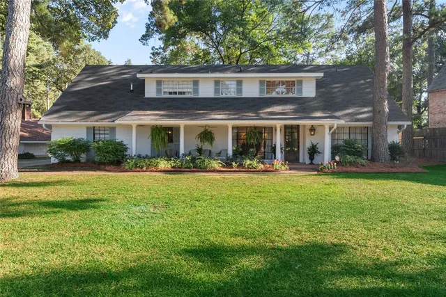 a view of house with a big yard and potted plants