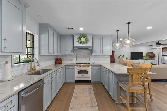 a large kitchen with granite countertop a large stove top oven sink and cabinets