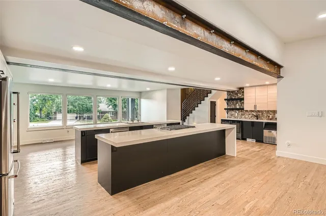 a large kitchen with kitchen island a stove a sink dishwasher and white cabinets with wooden floor