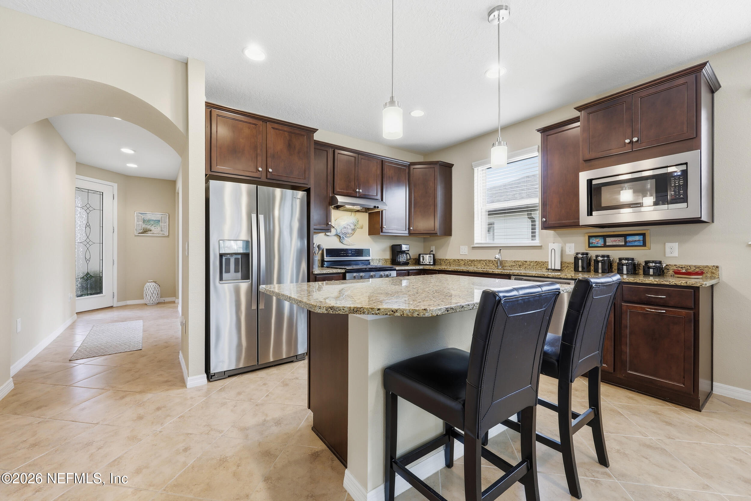 258 Rock Spring Loop St. Augustine, FL 32095 - Photo 8 of 31 a kitchen with kitchen island granite countertop wooden cabinets a refrigerator a stove a microwave oven a sink with island and chairs