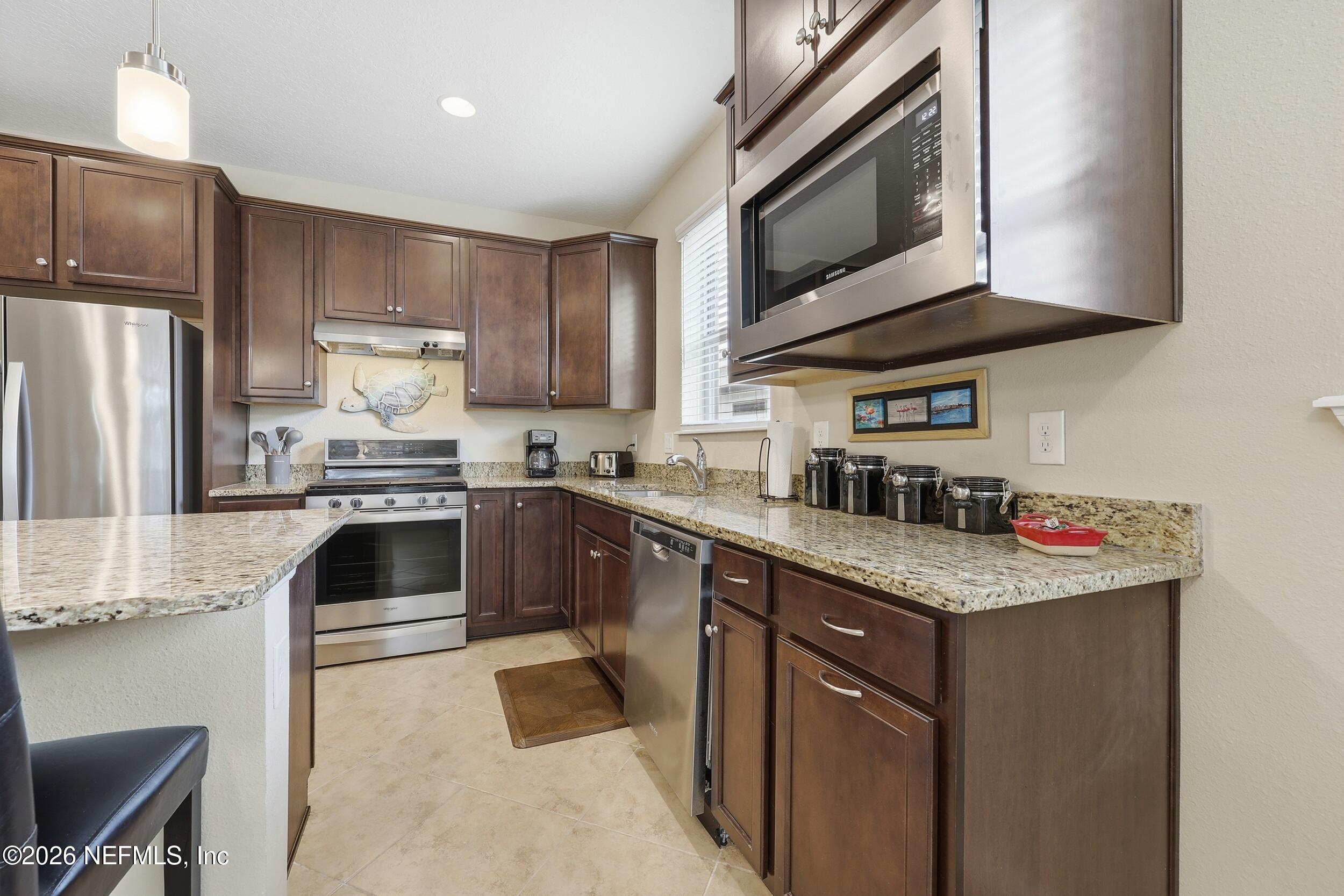 258 Rock Spring Loop St. Augustine, FL 32095 - Photo 9 of 31 a kitchen with stainless steel appliances granite countertop a sink stove microwave and refrigerator