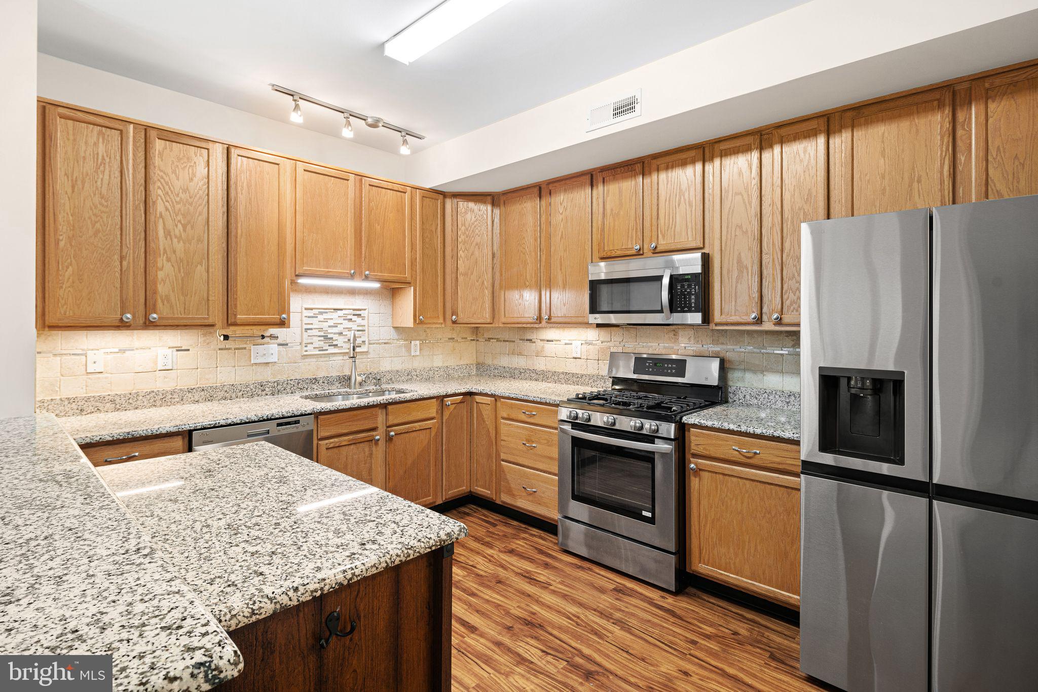 1364 Nicklaus Drive Springfield, PA 19064 - Photo 10 of 25 a kitchen with granite countertop wooden cabinets a stove top oven and stainless steel appliances