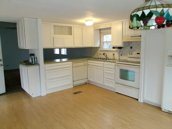 a kitchen with granite countertop white cabinets and white appliances