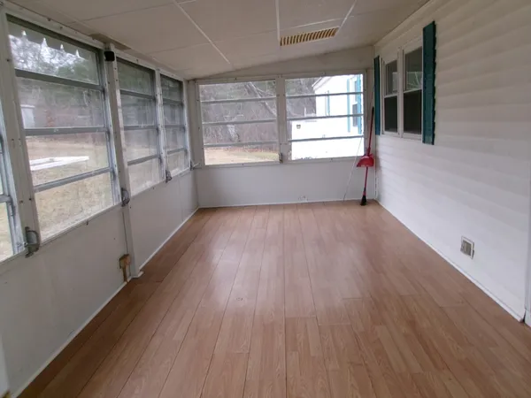 a view of an empty room with a window and wooden floor