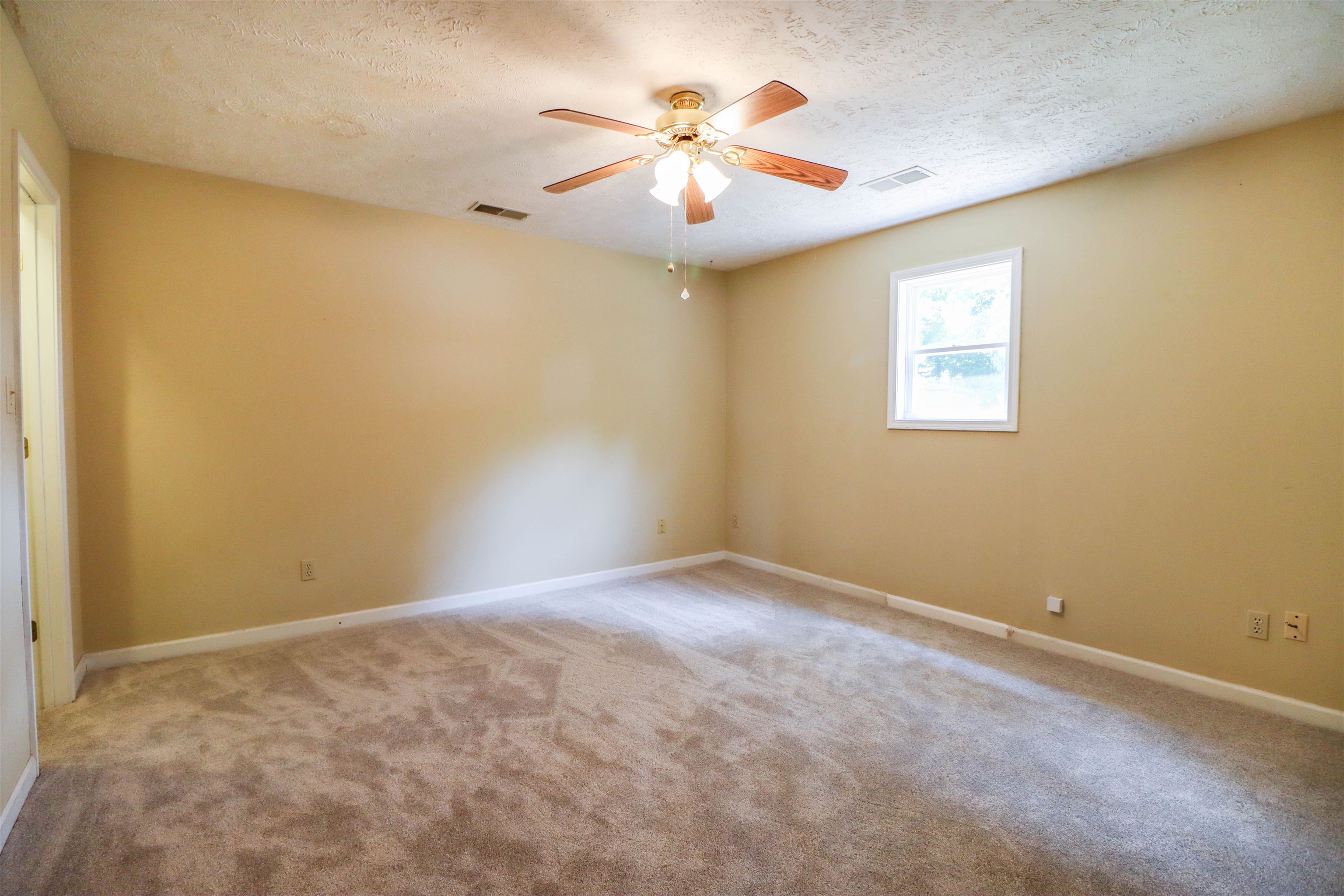 319 Jordan Street Ripley, TN 38063 - Photo 19 of 33 an empty room with a chandelier fan and windows