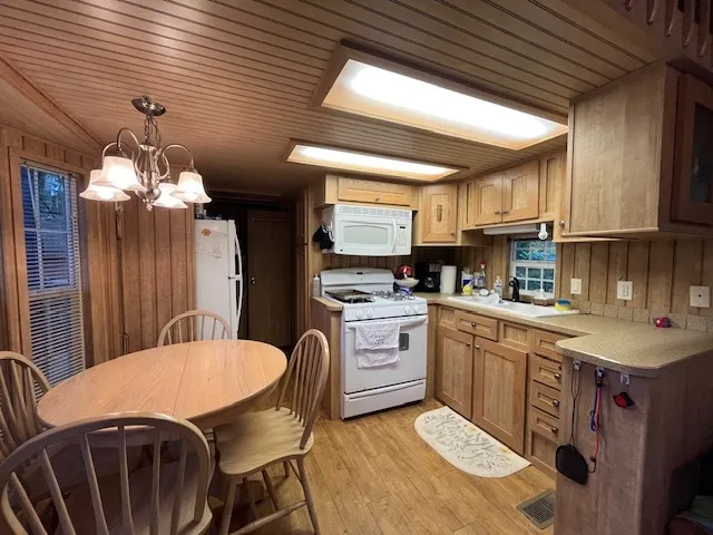 a kitchen with stainless steel appliances granite countertop a sink a stove a refrigerator a dining table and chairs