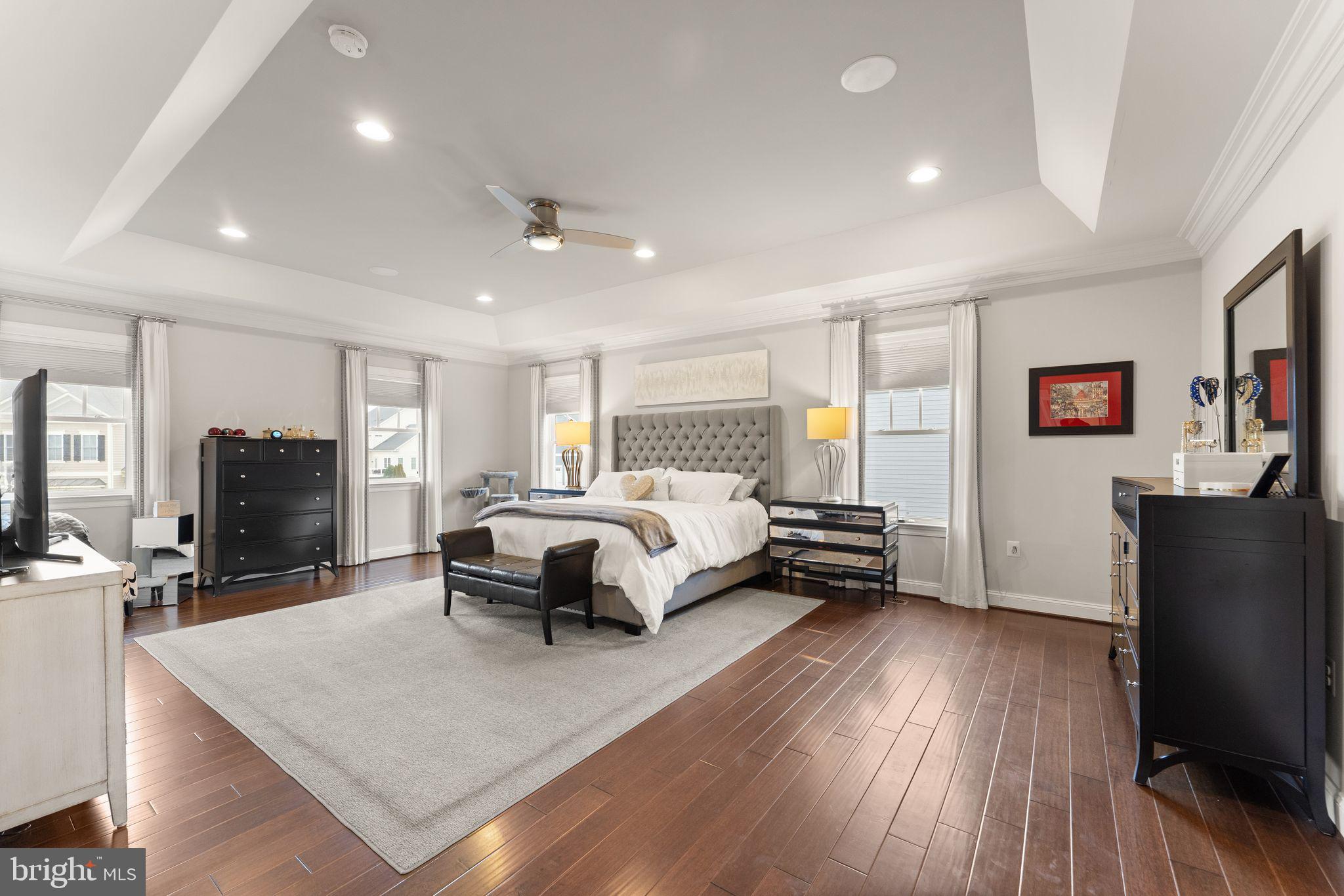 41865 Paddock Gate Place Ashburn, VA 20148 - Photo 37 of 99 a spacious bedroom with a bed a couch and a flat tv screen on the dresser