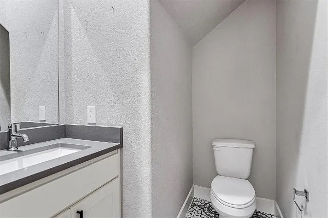a bathroom with a granite countertop toilet sink and mirror