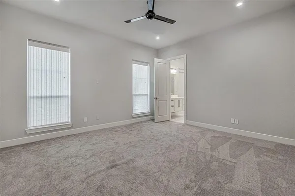 an empty room with chandelier fan and windows