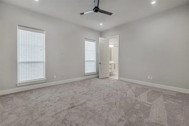 an empty room with chandelier fan and windows