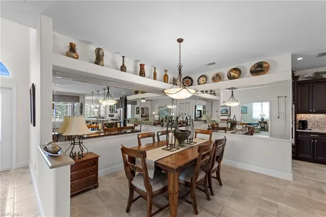 a view of a dining room and livingroom with furniture wooden floor a rug a flat screen tv a rug and a chandelier