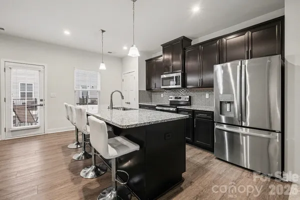 a kitchen with stainless steel appliances granite countertop a refrigerator a sink dishwasher a stove and a refrigerator with wooden floor