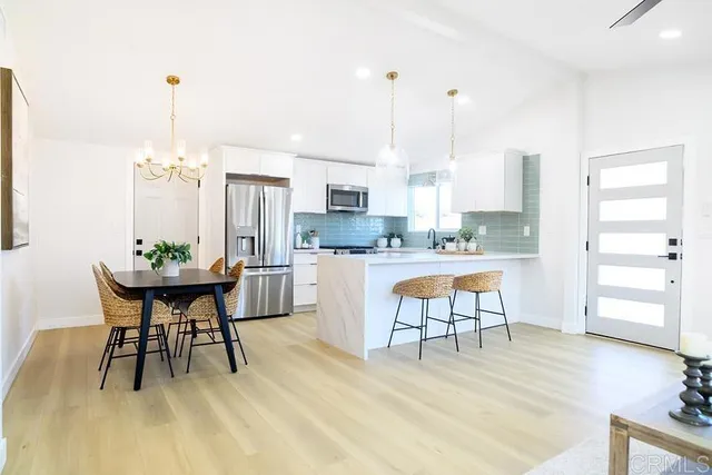 a kitchen with kitchen island a dining table chairs stainless steel appliances and cabinets