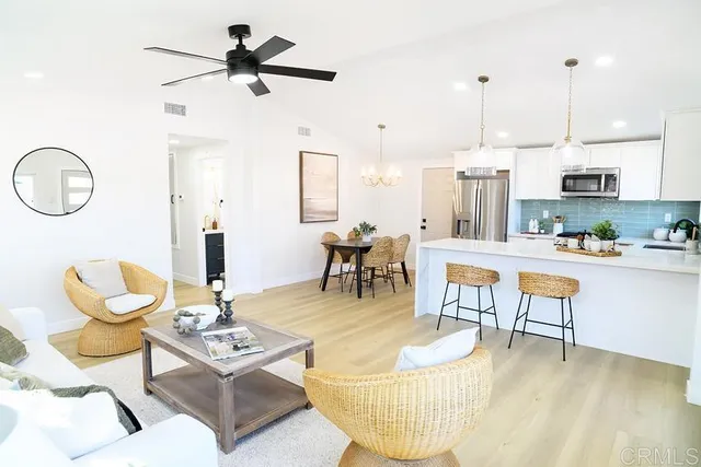 a living room with couches a coffee table and kitchen view with wooden floor