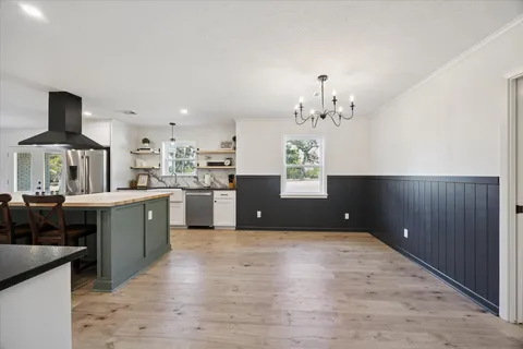 a open kitchen with kitchen island a sink dishwasher a stove and a refrigerator with wooden floor