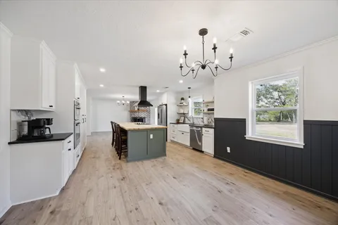a large kitchen with kitchen island a large counter space a sink appliances and cabinets