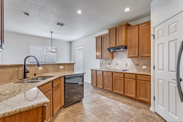 a kitchen with stainless steel appliances granite countertop a sink refrigerator and cabinets