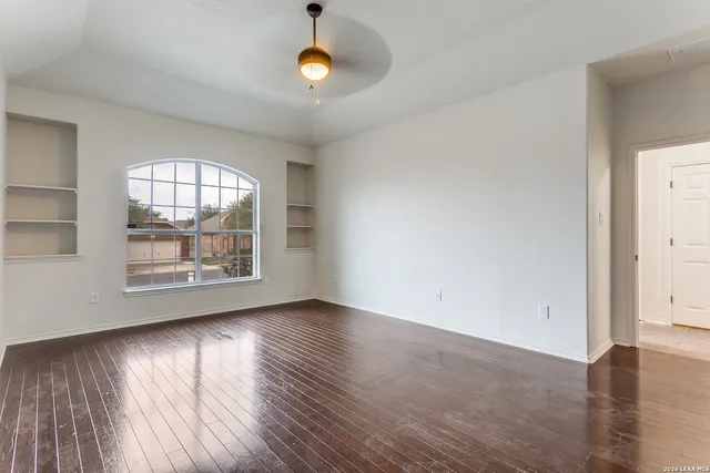 an empty room with wooden floor and windows