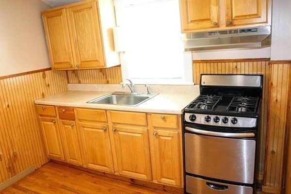 a kitchen with granite countertop a sink a stove and cabinets