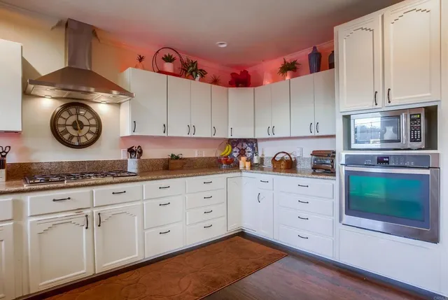 an open kitchen with wooden floor and stainless steel appliances