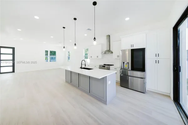 a kitchen with stainless steel appliances a stove a refrigerator a oven and white cabinets with wooden floor