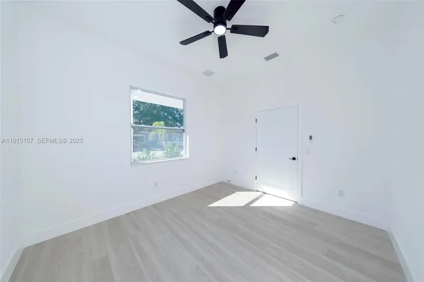 an empty room with wooden floor ceiling fan and windows