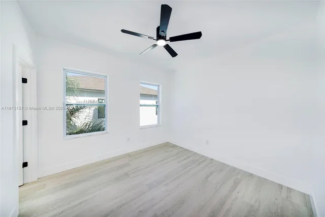 an empty room with wooden floor fan and windows