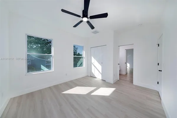 a view of empty room with wooden floor and fan