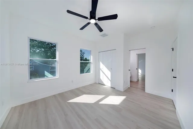 a view of empty room with wooden floor and fan